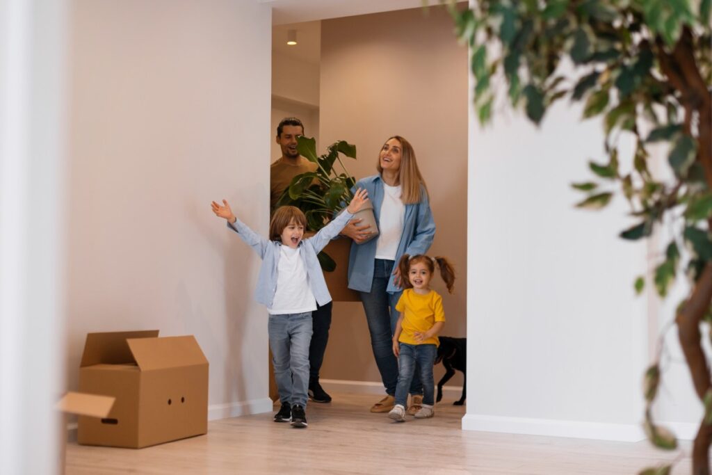 Familia feliz de pareja con dos niños entrando a casa nueva
